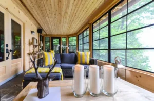 WeatherMaster™ Windows in a beautifully designed sunroom, featuring a warm wooden interior, stylish furniture, and large panoramic views of lush greenery.