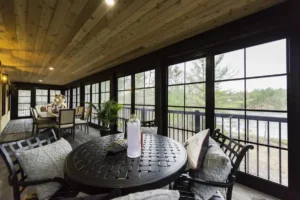 Inviting porch featuring Sunspace WeatherMaster™ Windows, black metal furniture, and picturesque lake views.