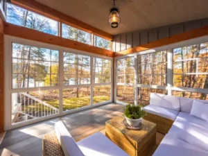 WeatherMaster™ Windows in a cozy sunroom with large clear panels, offering a bright, airy space with a scenic outdoor view