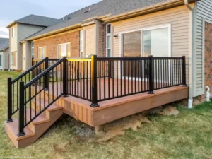 Aluminum decking with a railing and stairs leading to a front door, showcasing a modern outdoor design.