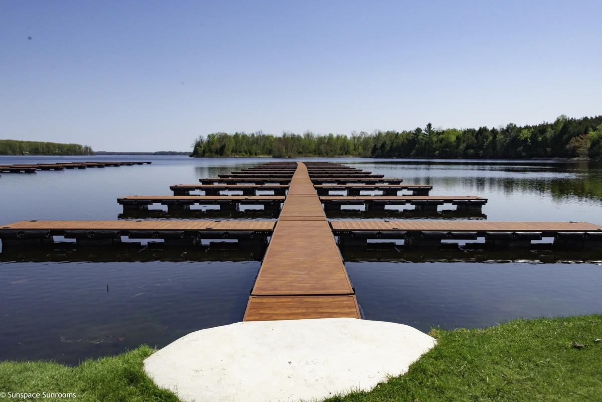 Elegant cedar-finish Aluminum Decking with a frameless glass railing, providing clear, unobstructed views of the surrounding forest.