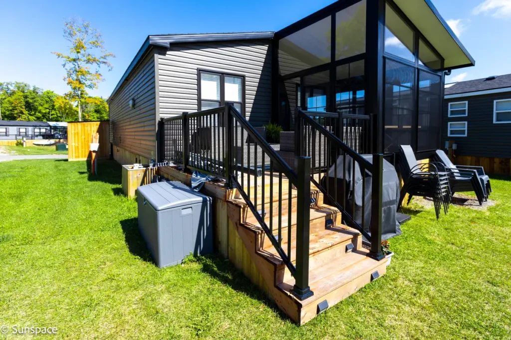 A charming small house with a deck and patio, illustrating the RV/Resort Living experience and inviting outdoor space.