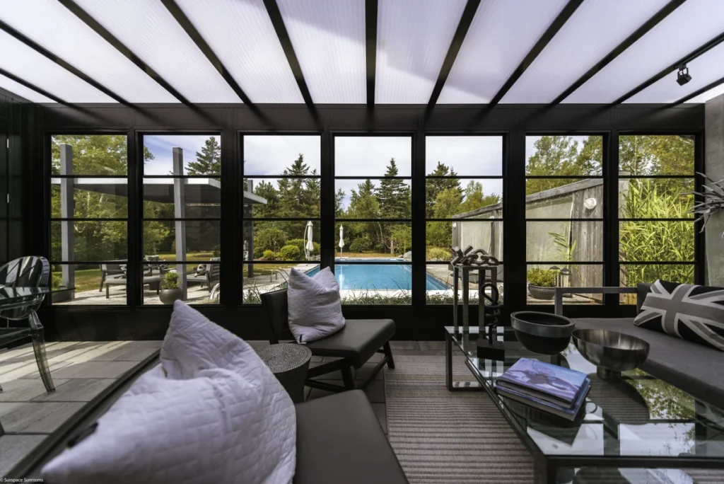 Sunrooms Model 200 of a living room with a pool and expansive glass walls, blending indoor and outdoor spaces.