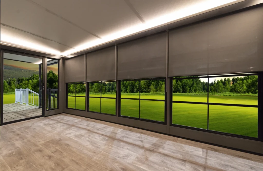 Modern sunshades partially drawn over large windows, revealing a patio and green landscape.