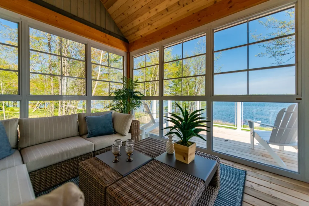 Bright Sunroom with wicker seating and expansive windows overlooking tranquil water, showcasing WeatherMaster™ Windows & Doors.