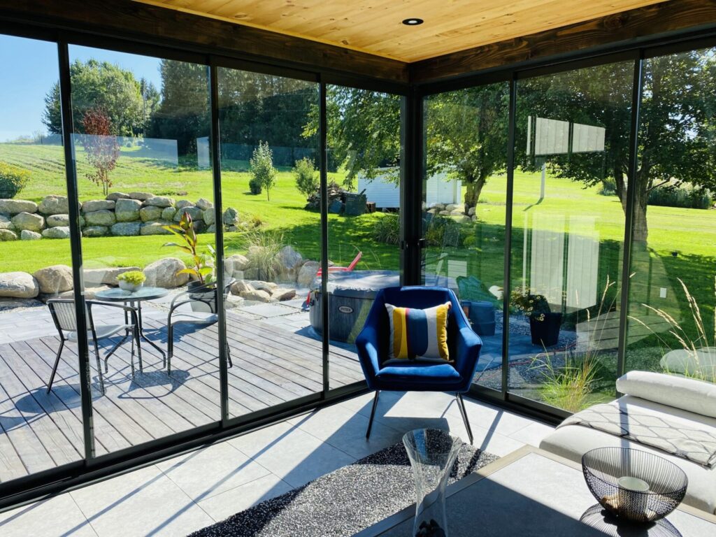 Modern Novasun HORIZON-Plus sunroom with floor-to-ceiling glass panels overlooking a lush backyard and patio.