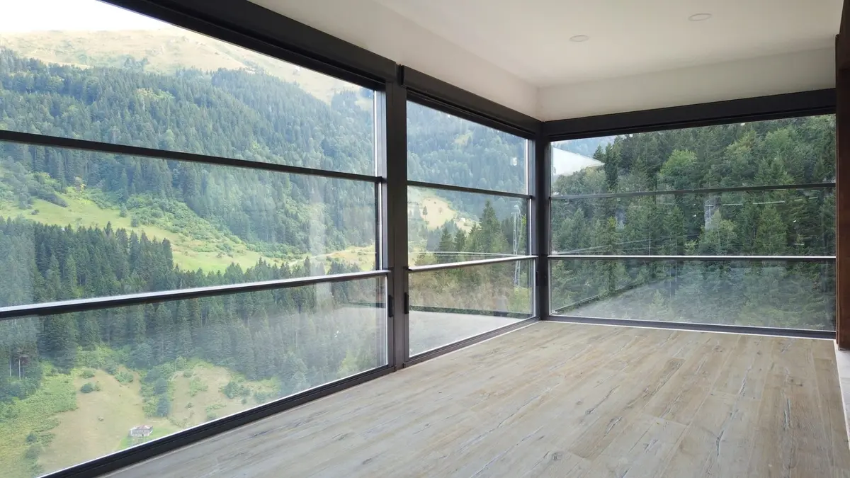 Interior of a room with a large window displaying a breathtaking mountain range, highlighting the vertigo plus