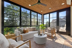 Sunroom with a ceiling fan and cozy couch, highlighting a porch conversion designed for comfort and relaxation.