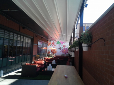 Retractable awning with custom striped fabric on brick home