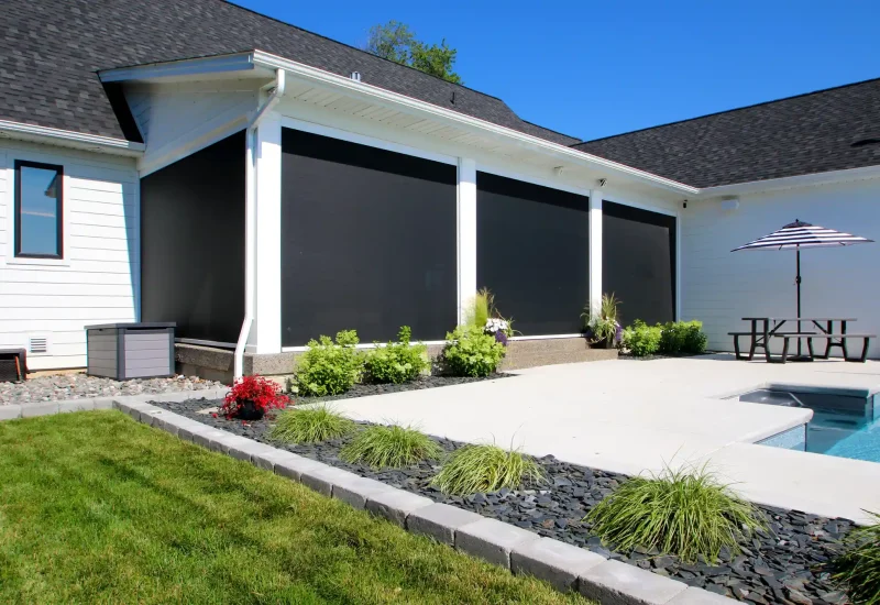 Outdoor pool scene with a retractable black screen and a comfortable patio area for leisure activities.