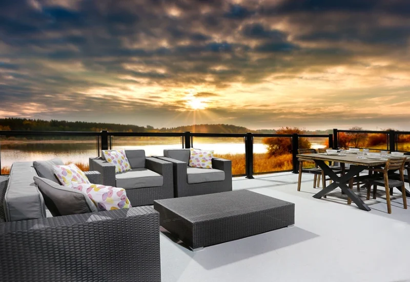 A patio featuring furniture and a sunset view, showcasing the Topless Glass Railing for an unobstructed sightline.