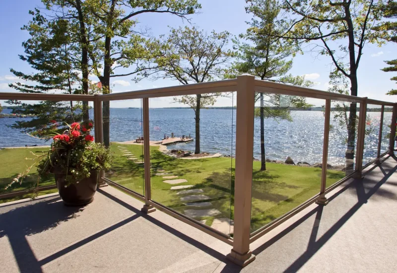 Topless Glass Railing provides a clear view of the water and trees in the background, enhancing the outdoor experience.