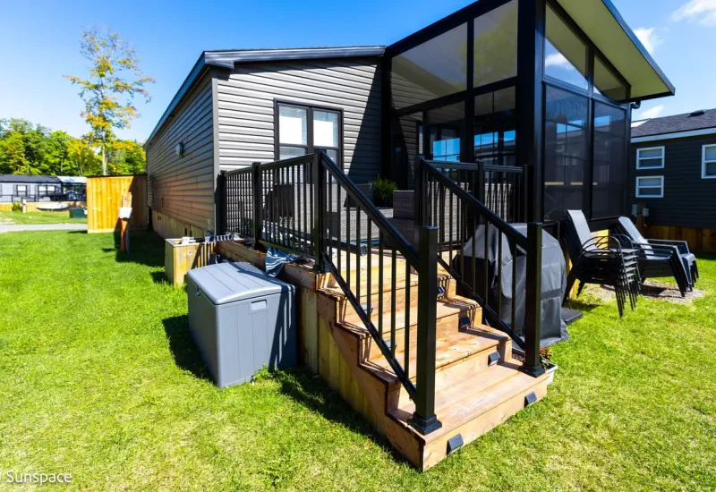 A charming small house with a deck and patio, illustrating the RV/Resort Living experience and inviting outdoor space.