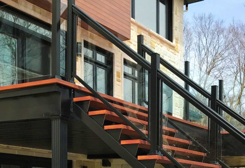 Black and red Aluminum Railing with Glass, featuring stairs leading up to a house entrance.