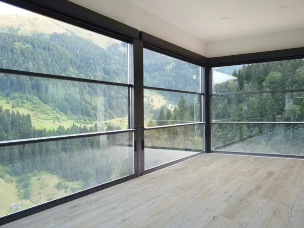 Interior of a room with a large window displaying a breathtaking mountain range, highlighting the vertigo plus
