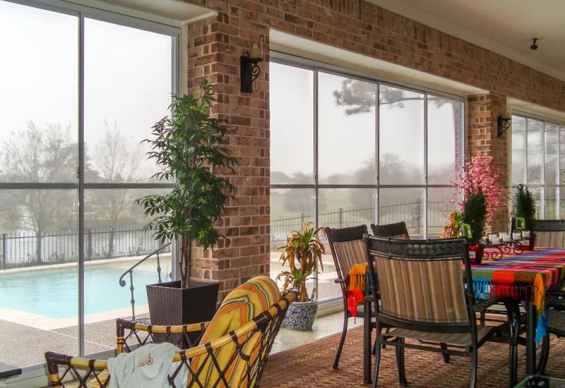 Outdoor patio with a table, chairs, and a pool, highlighting the WeatherMaster™ Horizontal 2 to 4 Track Windows/Doors.