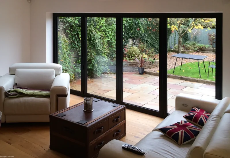 A cozy living room featuring a sofa and a WeatherMaster™ Plus Bi-Fold Door leading to an outdoor space.